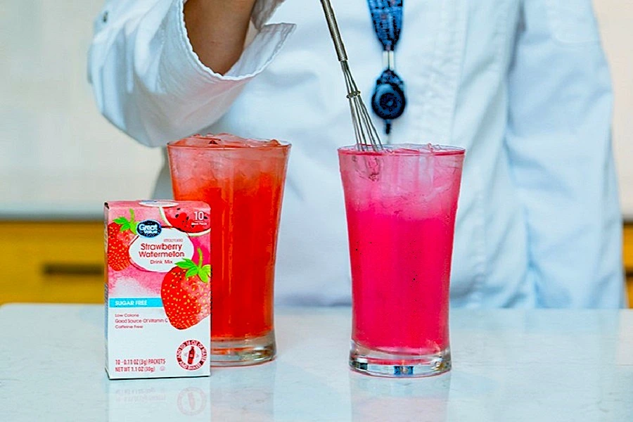 red liquid in two glasses with man’s hand dipping mixer in one glass